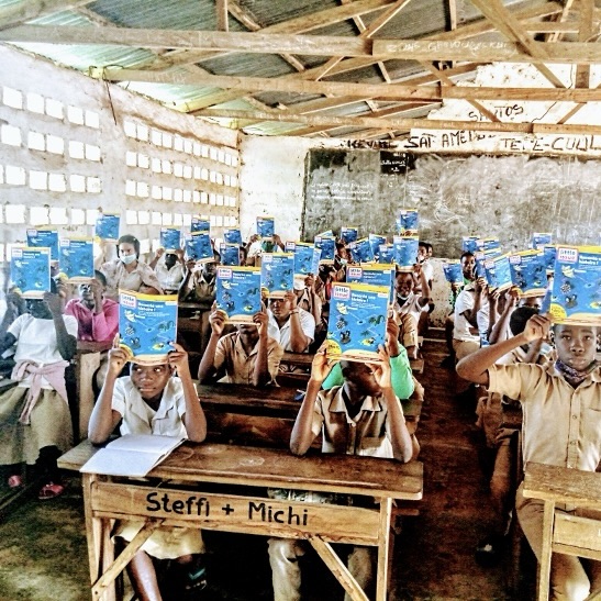 School children in Togo holding a book "Little Issue" above their heads