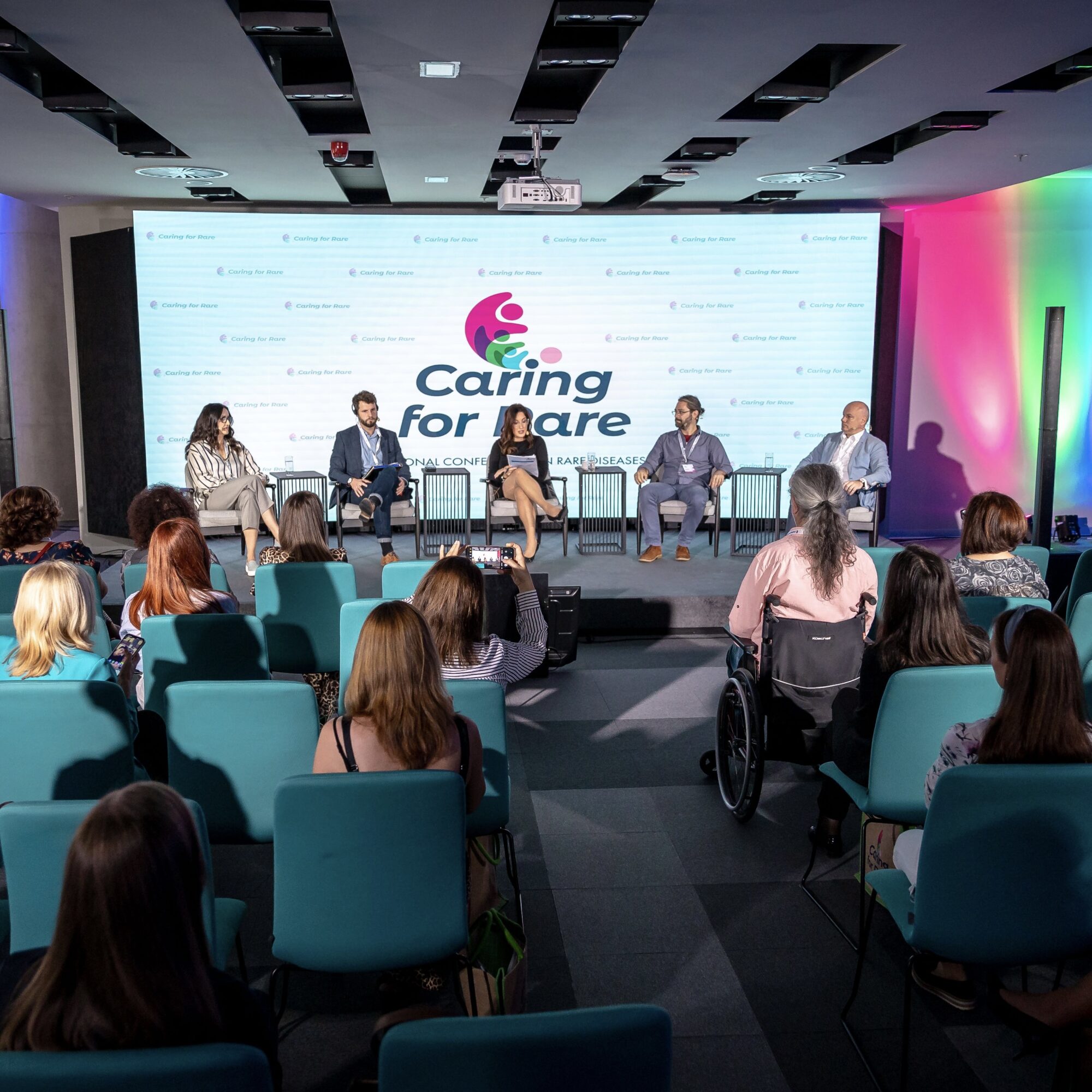 Caring for Rare conference with panelists on stage and a diverse public